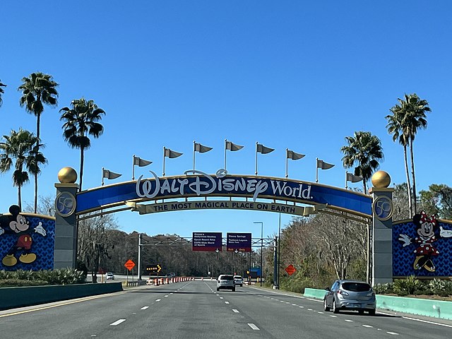 An entrance arch to Walt Disney World Resort / Wikipedia / Benoit Prieur 
Link: https://en.wikipedia.org/wiki/Walt_Disney_World#/media/File:Portail_Disneyworld_%C3%A0_l'arriv%C3%A9e_%C3%A0_Orlando_au-dessus_de_la_voie_rapide_(janvier_2022).JPG 
